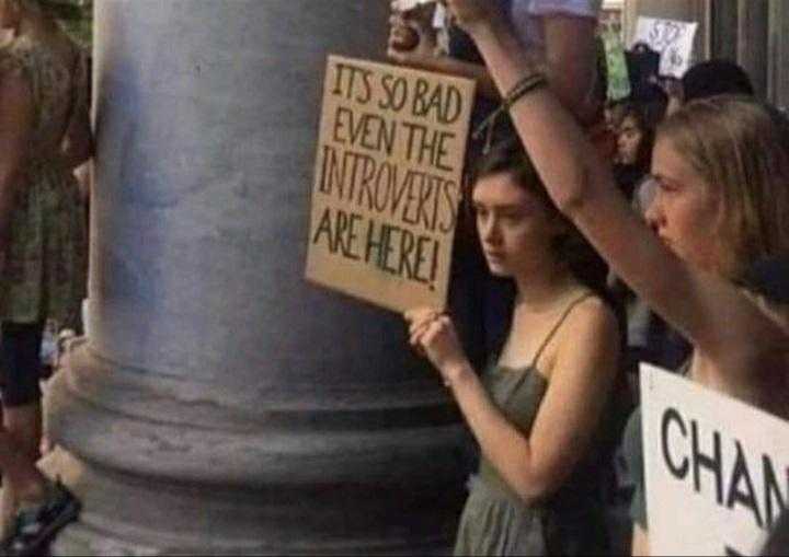 people holding signs and standing around a column with a sign