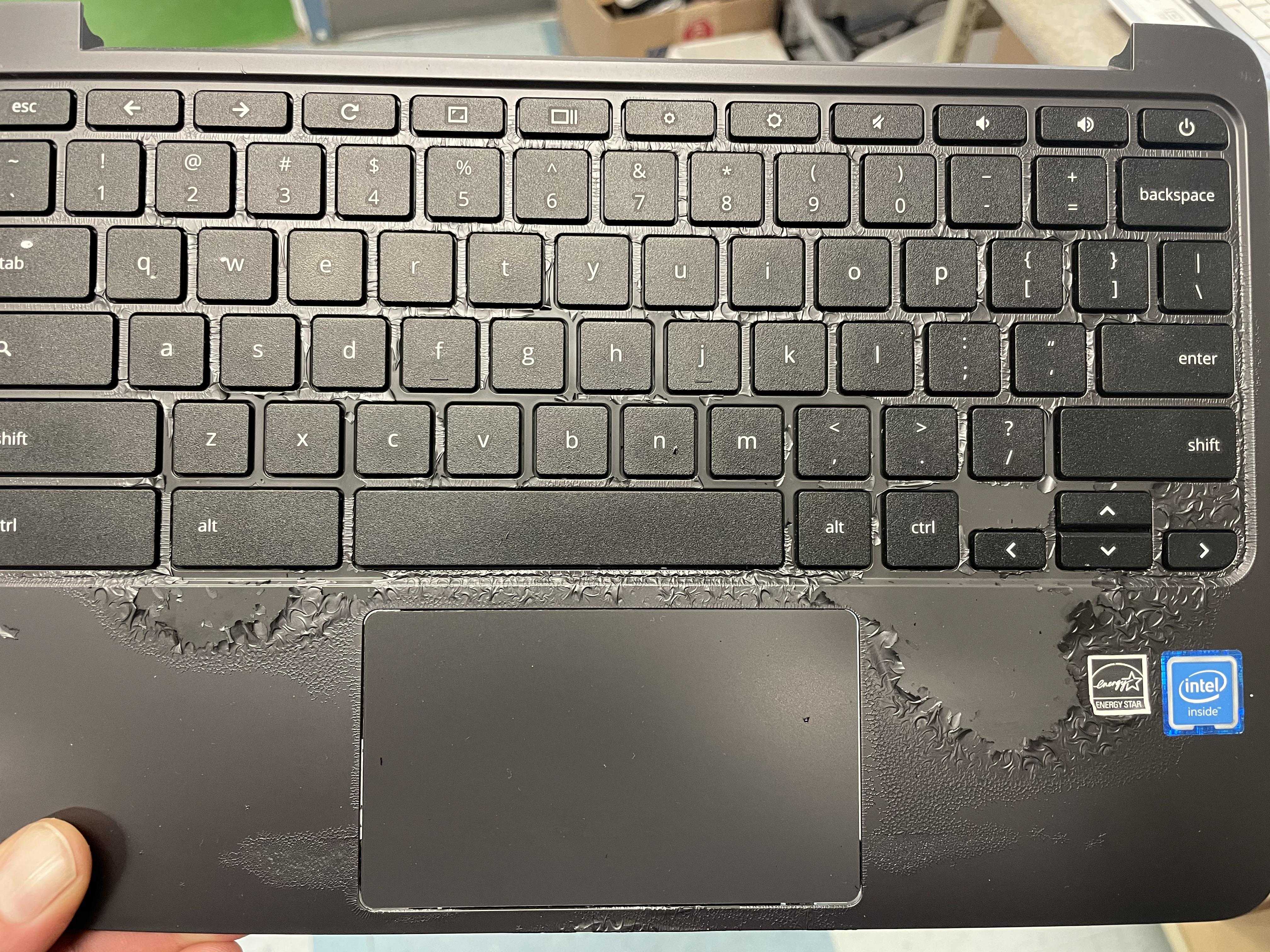 someone is holding a laptop with a broken keyboard and a broken mouse