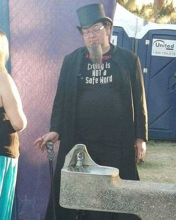 there is a man with a top hat and cane standing next to a water fountain