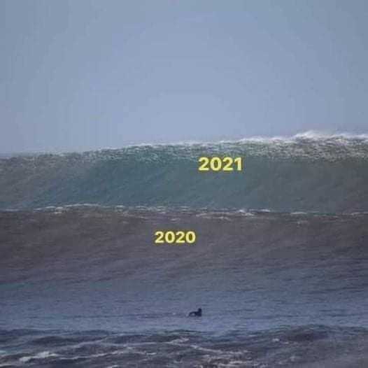 surfers riding a wave in the ocean with a large wave in the background