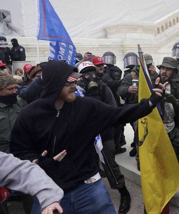 protestors in riot gear and helmets are holding flags