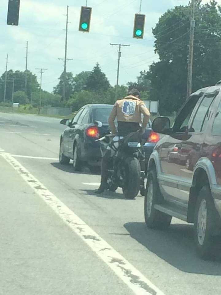 cars and motorcycles stopped at a traffic light on a busy street