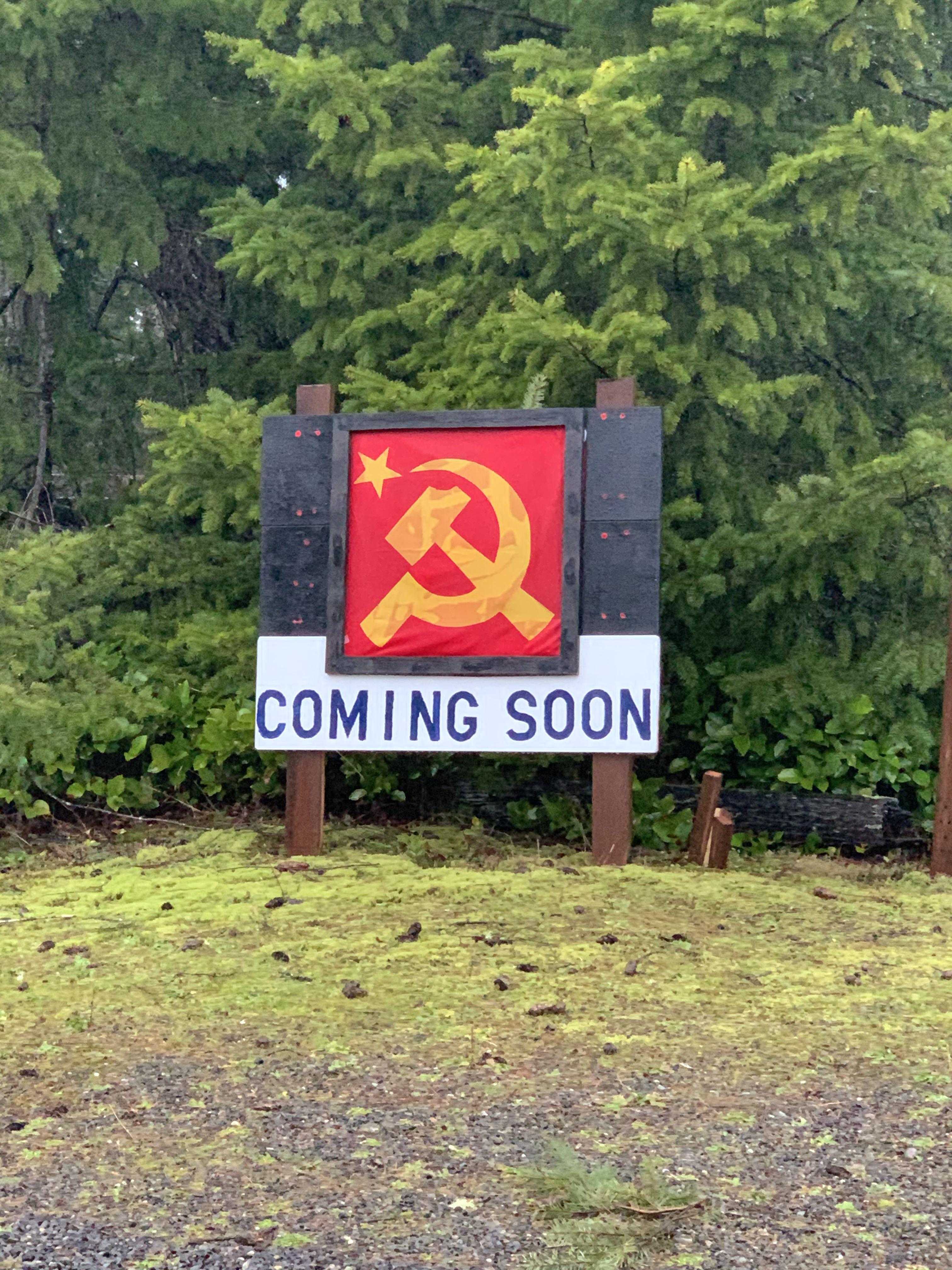 there is a sign that says coming soon in front of a forest