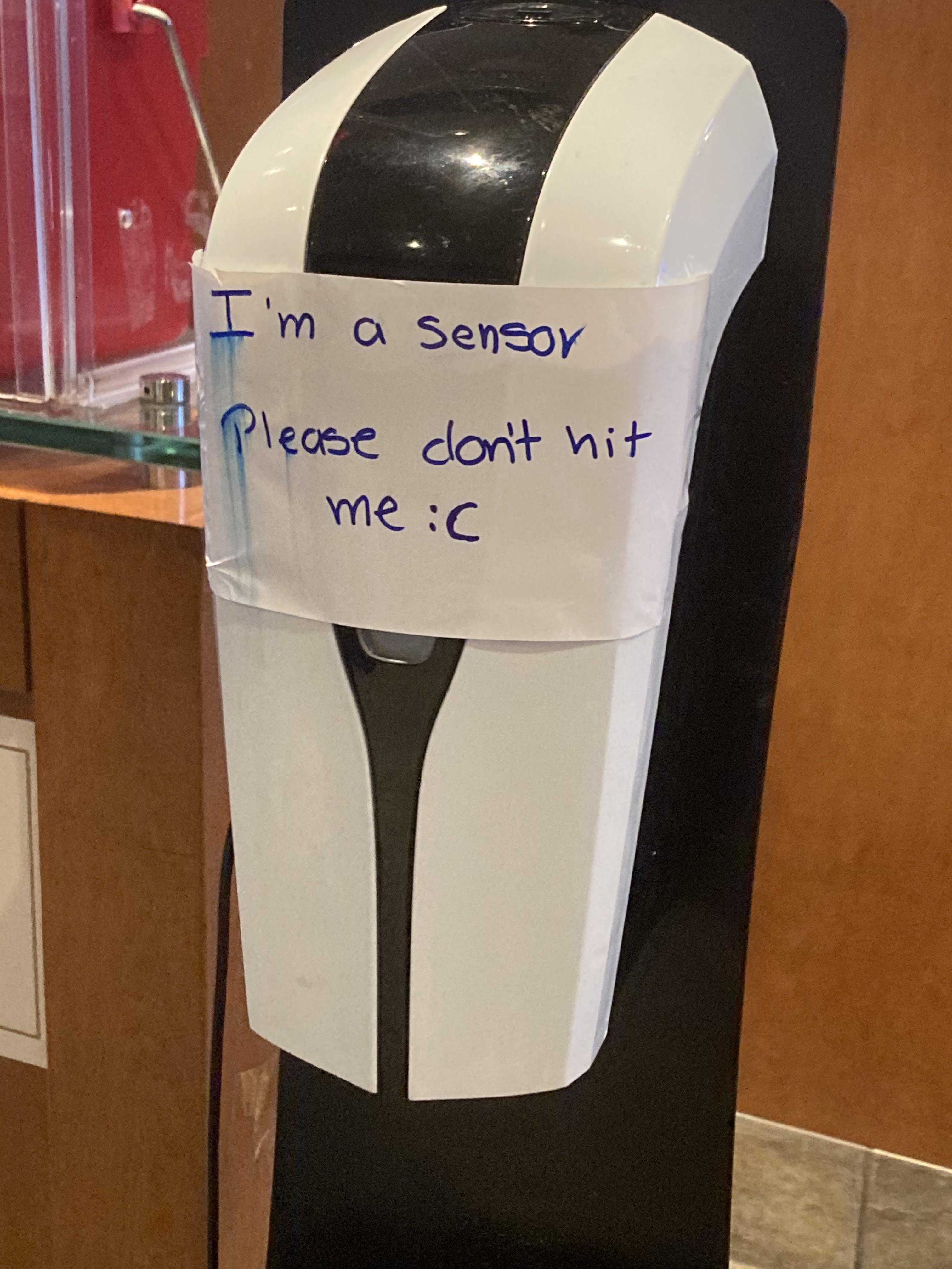 there is a sign on a black and white paper towel dispenser