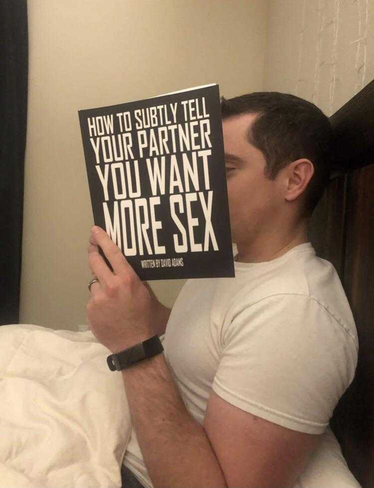 man sitting in bed holding a book with a quote on it