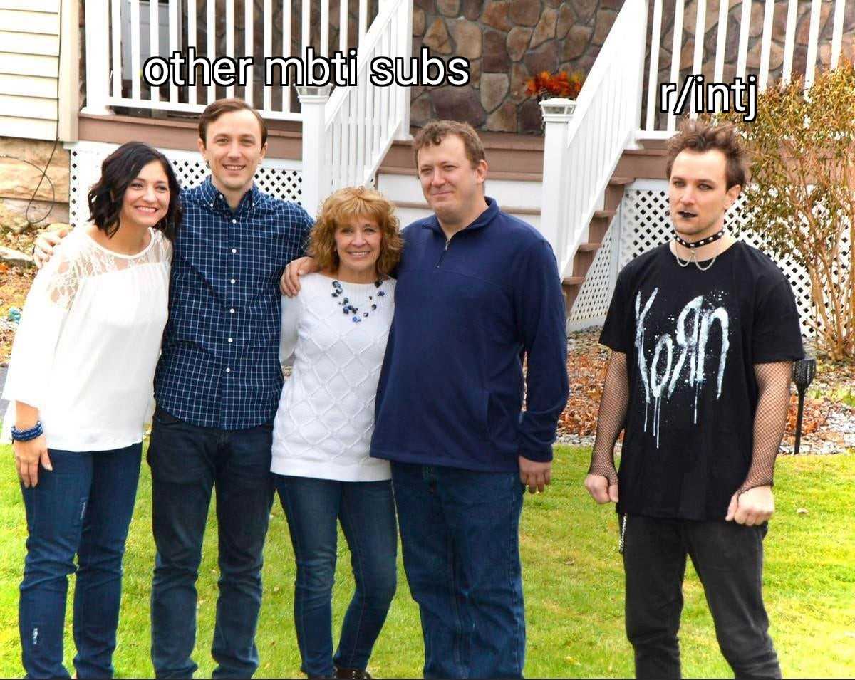 there are four people standing together in front of a house