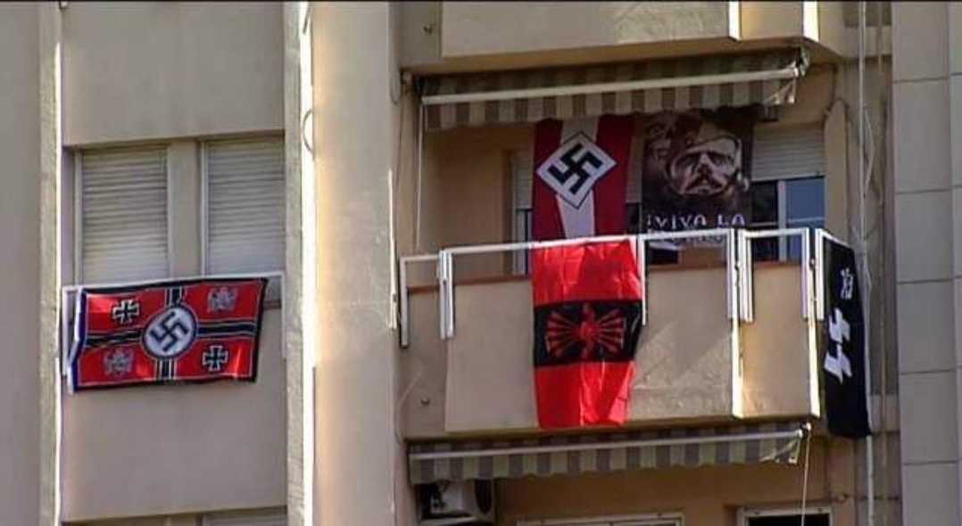 flags are hung on a balcony of a building with a balcony