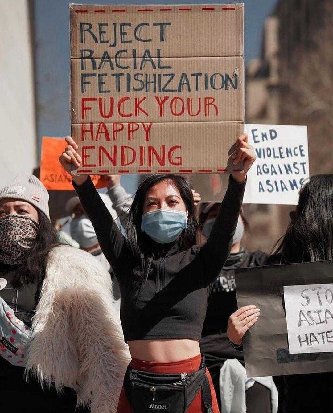 people holding signs and masks in a protest against racism