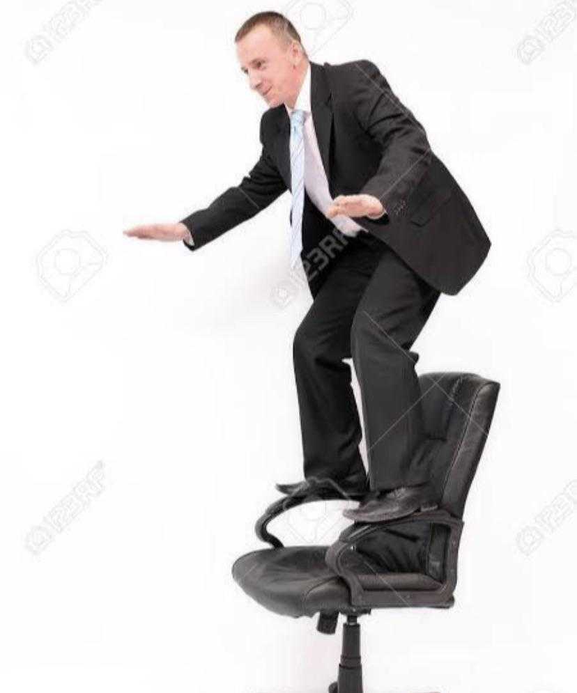 a man in a suit is standing on a chair and pointing at something