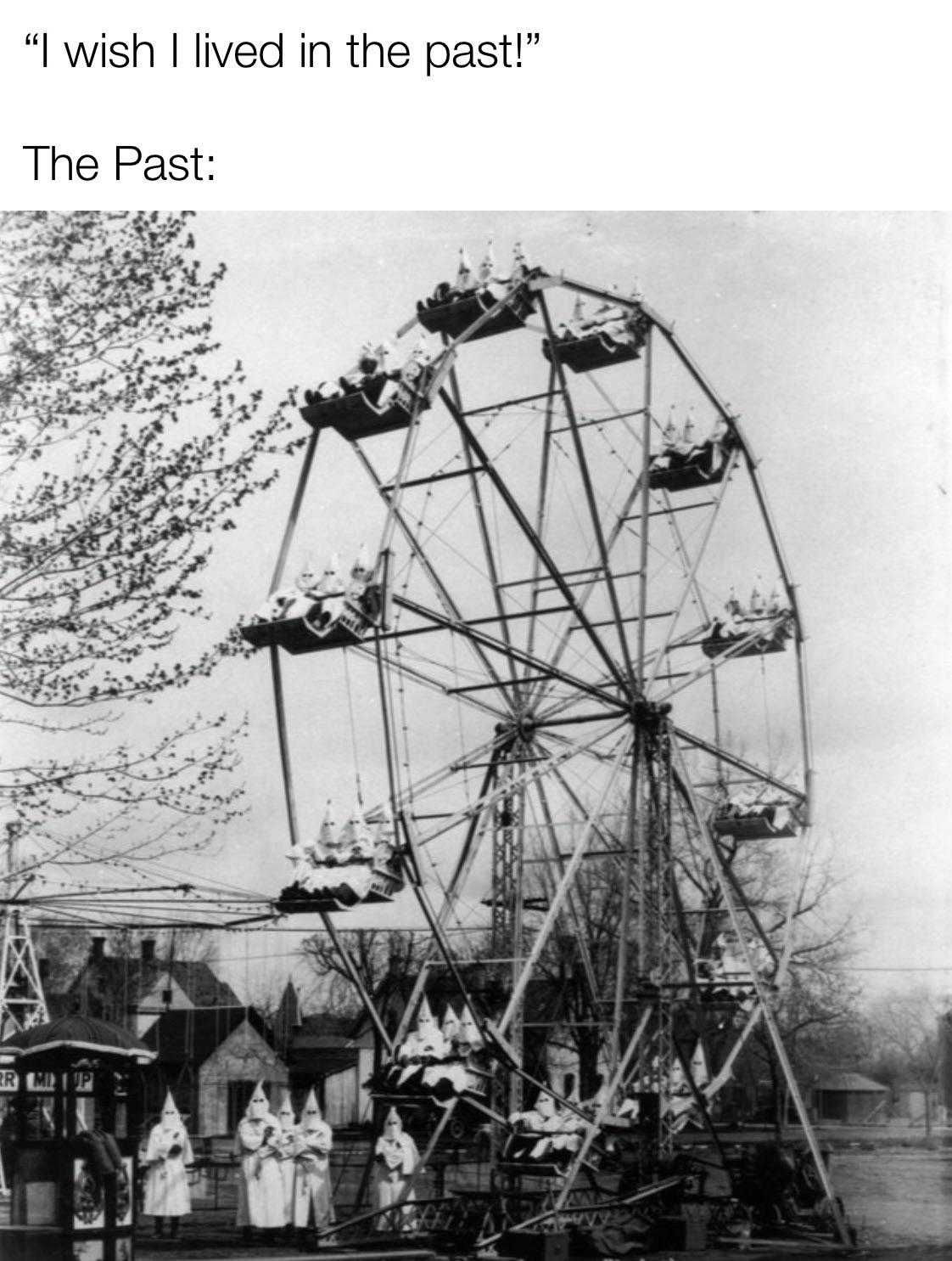 a black and white photo of a ferris wheel with people standing around it