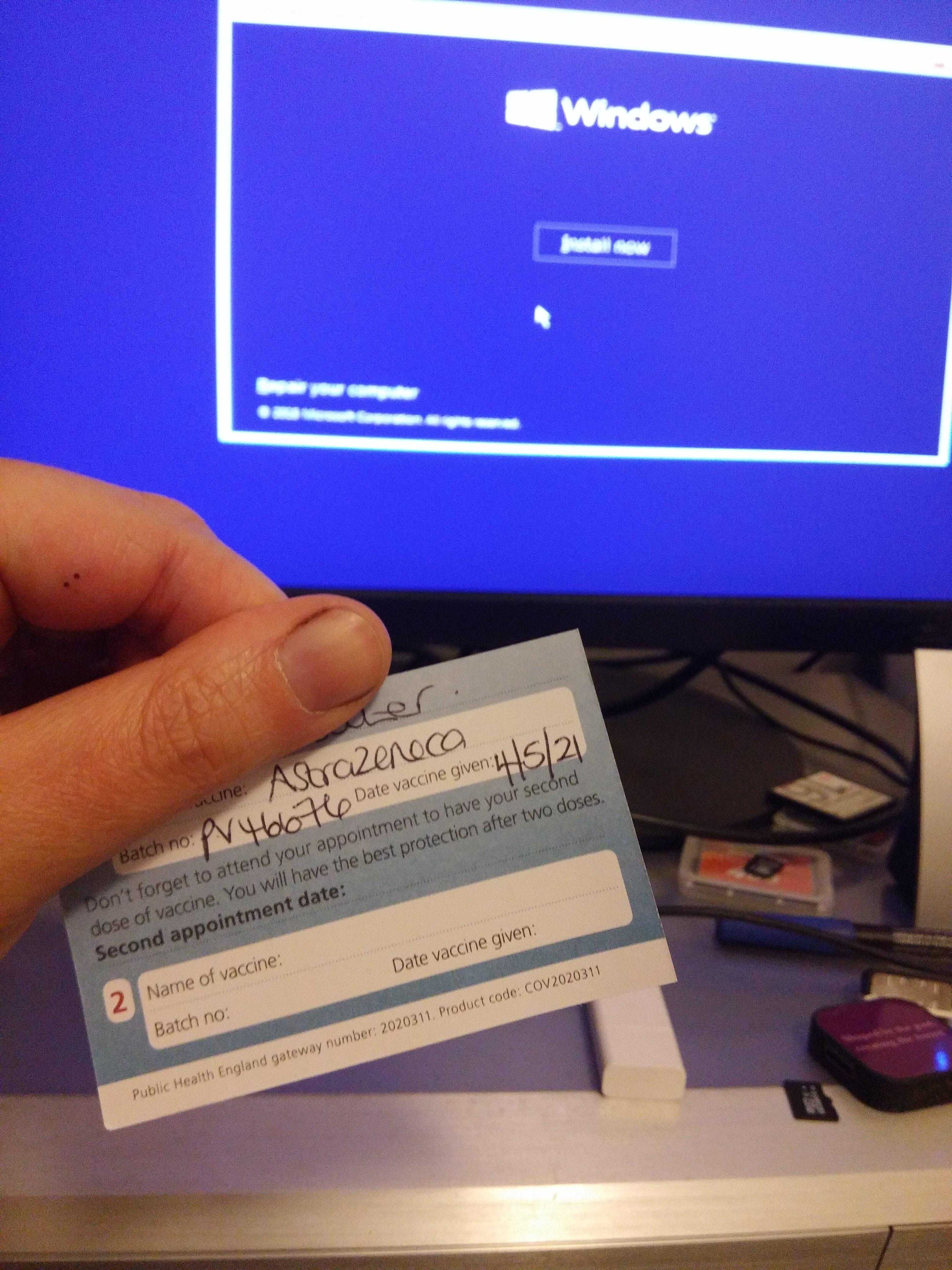 someone holding a business card in front of a computer monitor