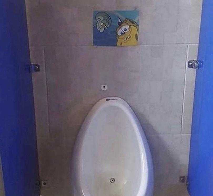 there is a urinal in a bathroom with a spongeie painting on the wall