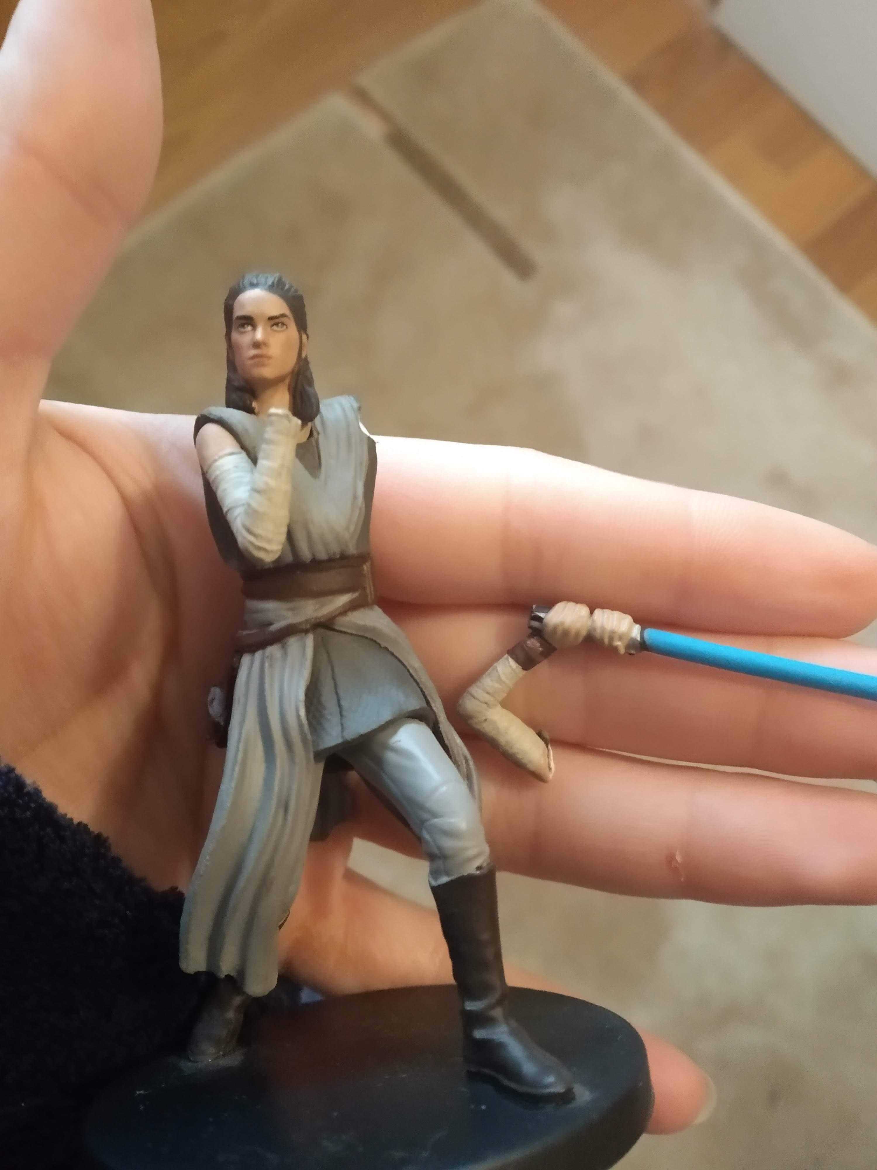 someone is holding a toy figure of a man with a blue light saber