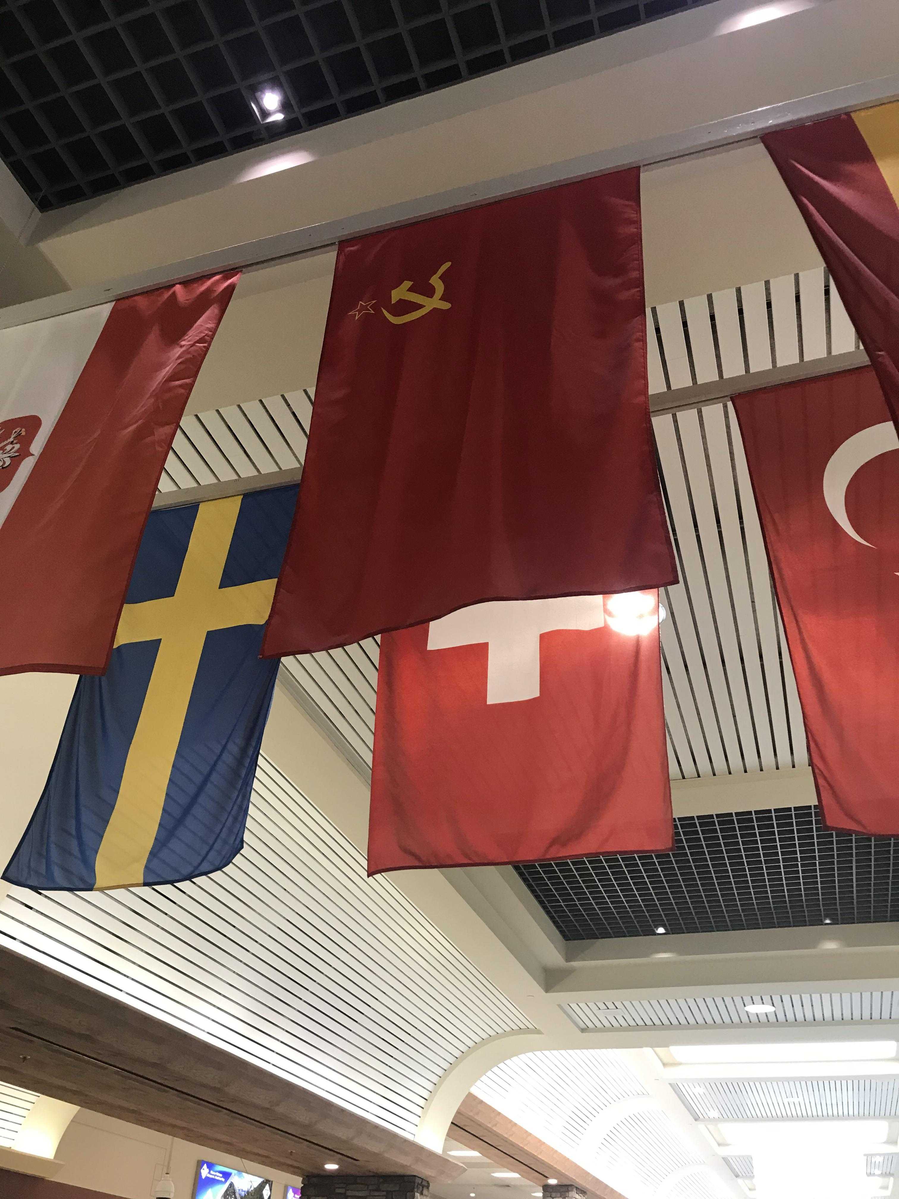 flags hanging from the ceiling of a building with a clock