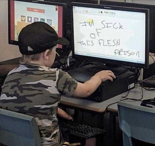 boy sitting at a desk with two computer monitors and a keyboard