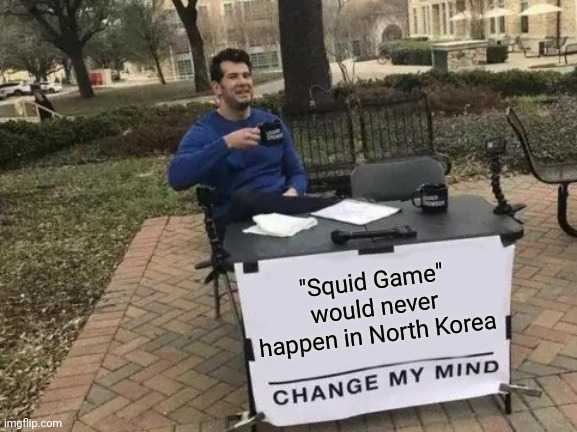 man sitting at a table with a sign that says squid game would never happen in north korea