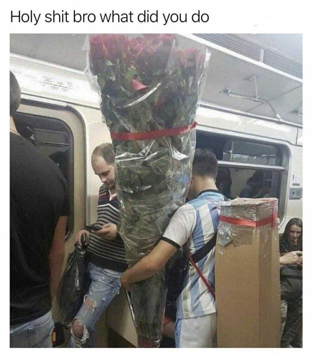 there are people standing on a subway train with a bunch of flowers