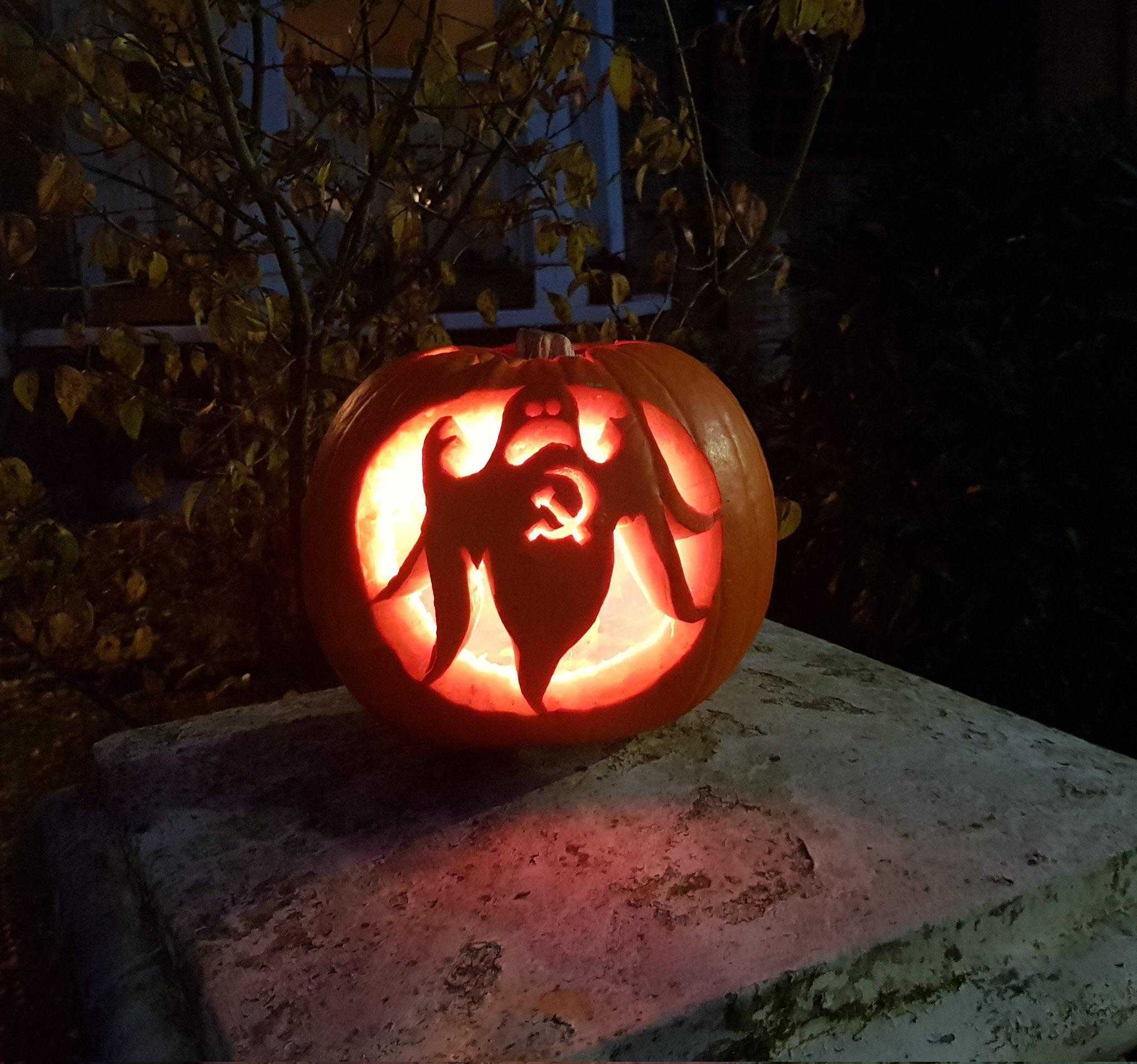 pumpkin with a face carved into it sitting on a stone