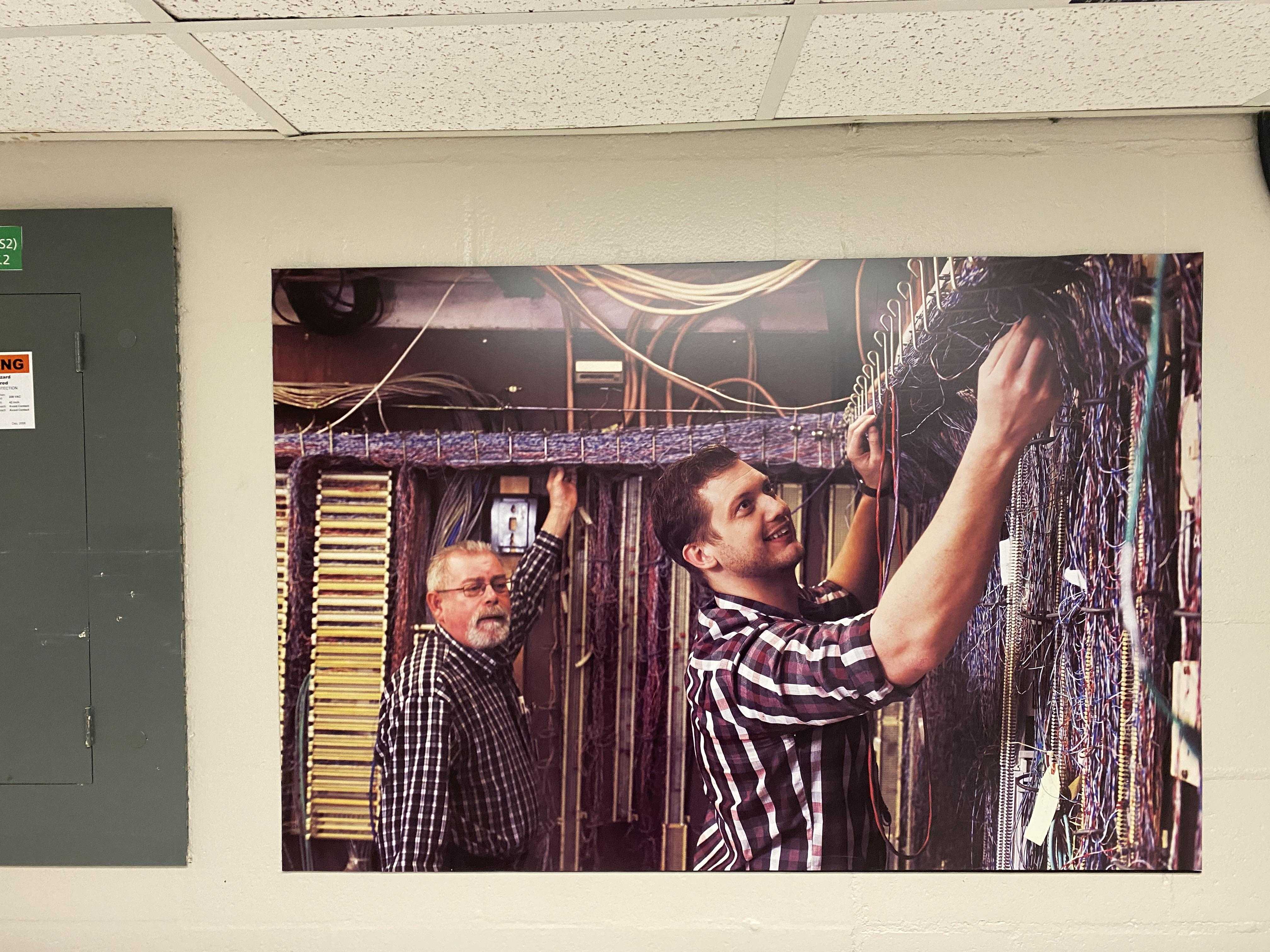 there is a man that is fixing a picture on the wall