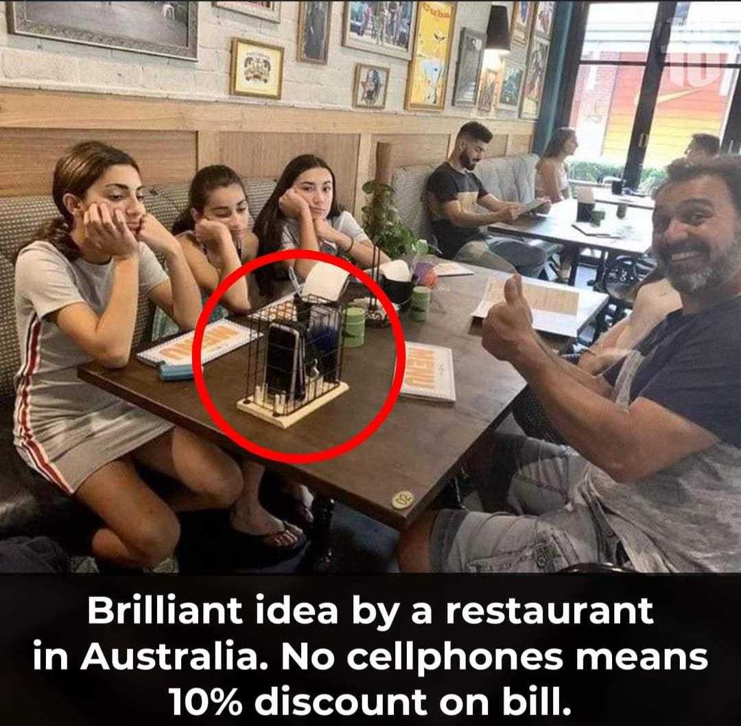 there are people sitting at a table with drinks and a phone