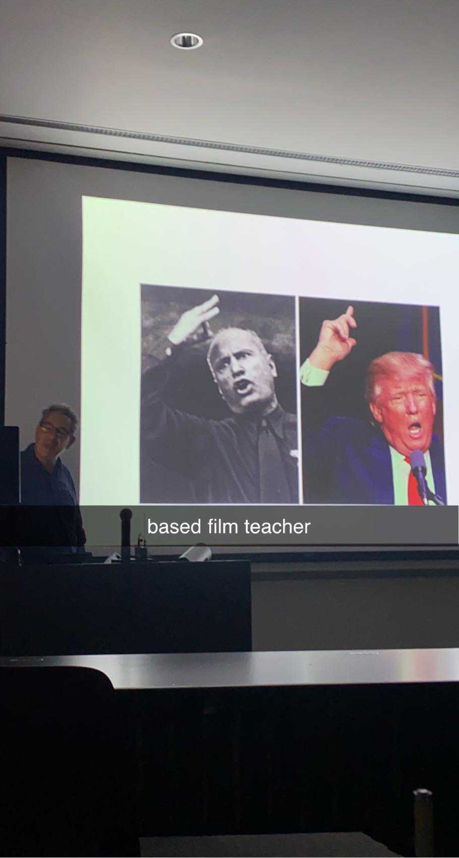 there are two men sitting at a table in front of a projector screen