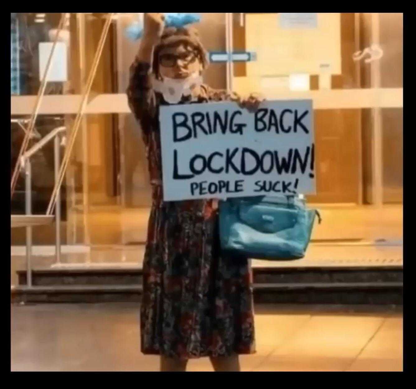 woman holding a sign saying bring back lockdown people suck