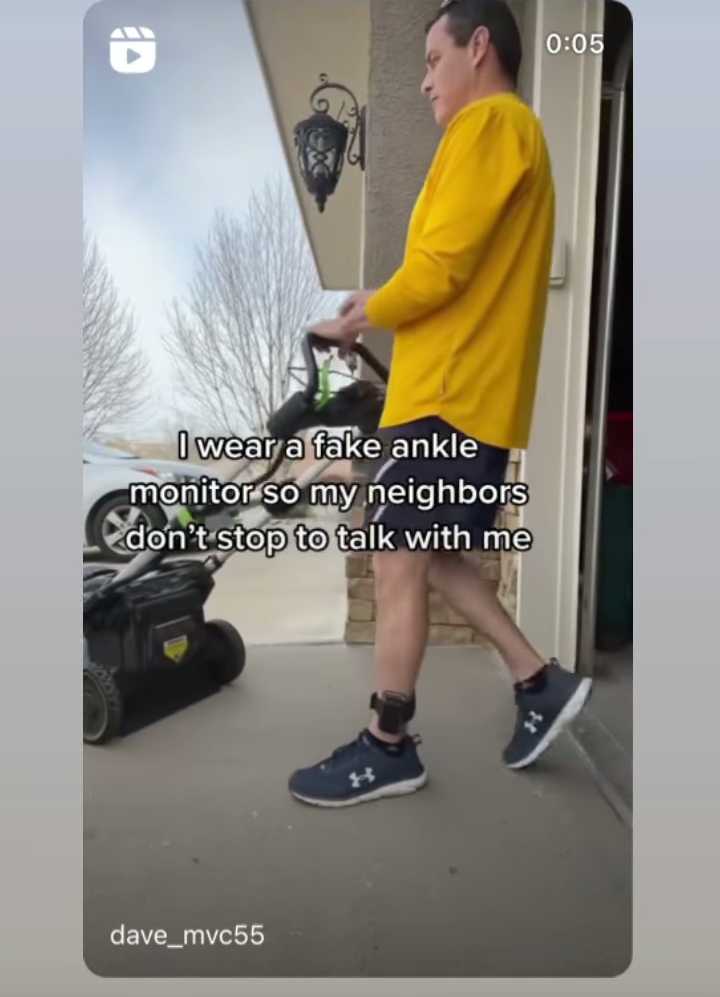 man in yellow shirt walking with a lawn mower