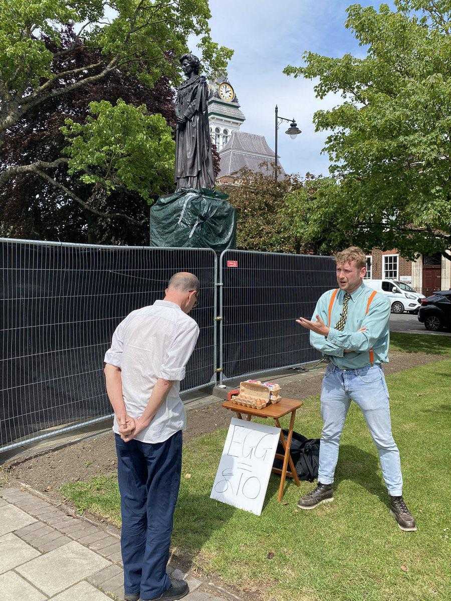 people standing around a statue of a man with a sign