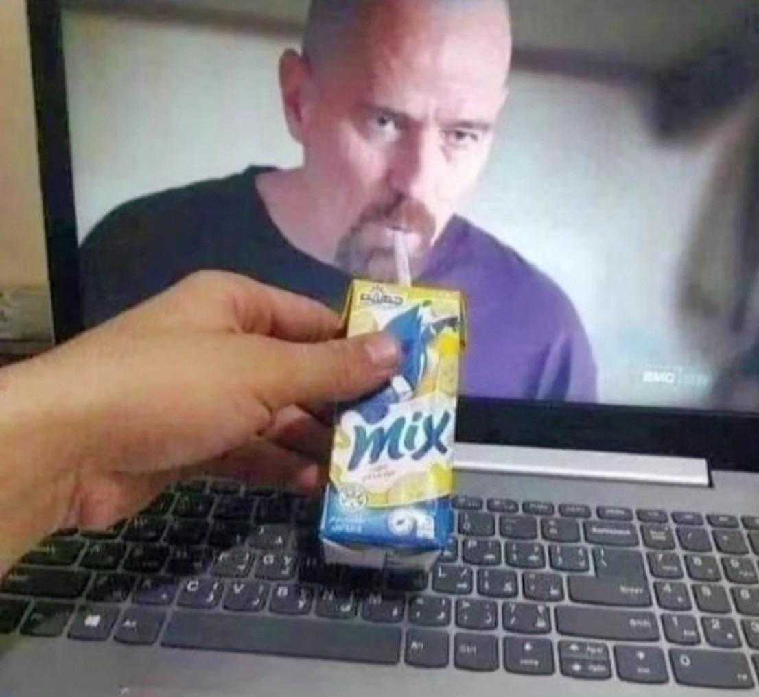 someone is holding a carton of milk in front of a laptop