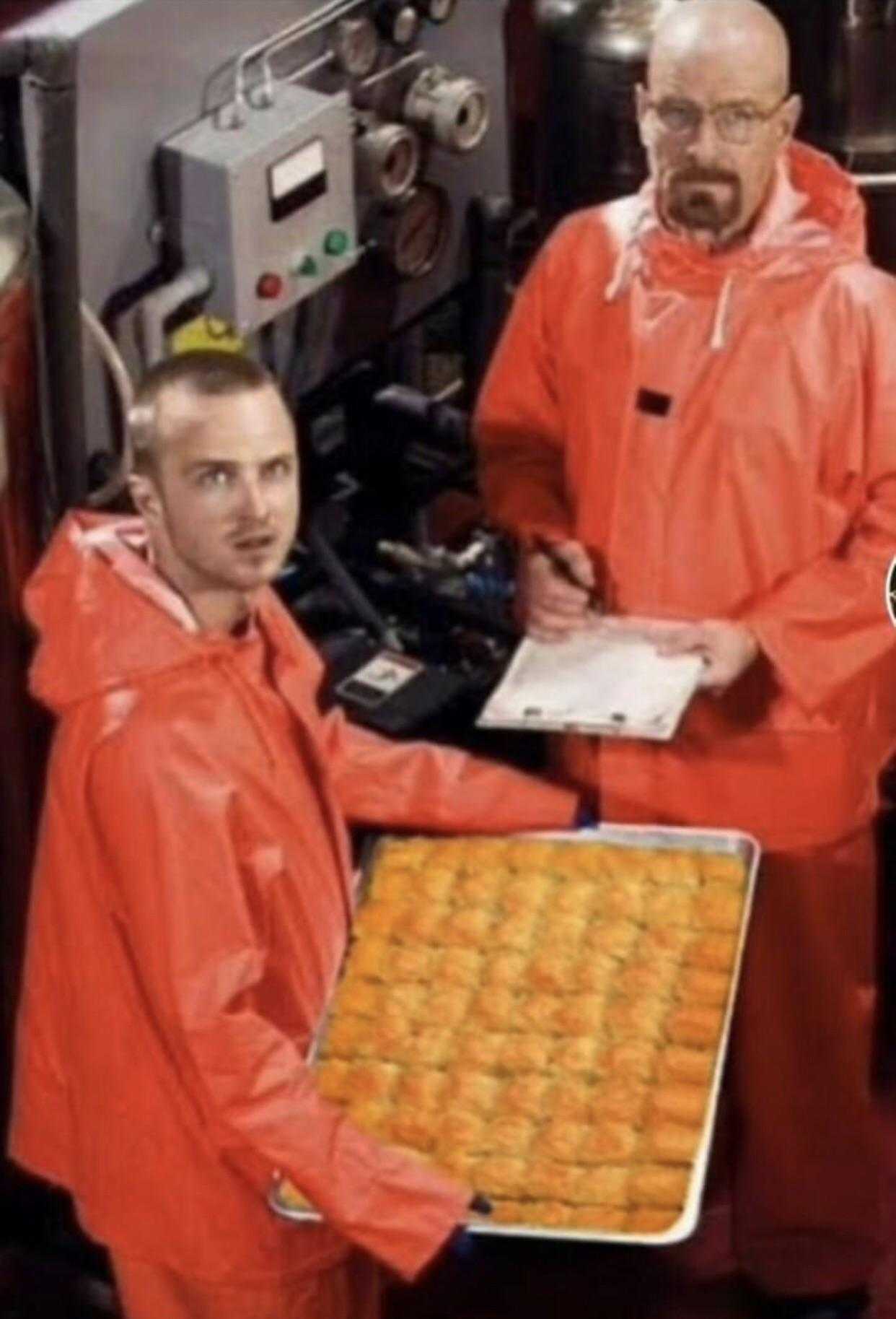 two men in orange rain suits holding a tray of food