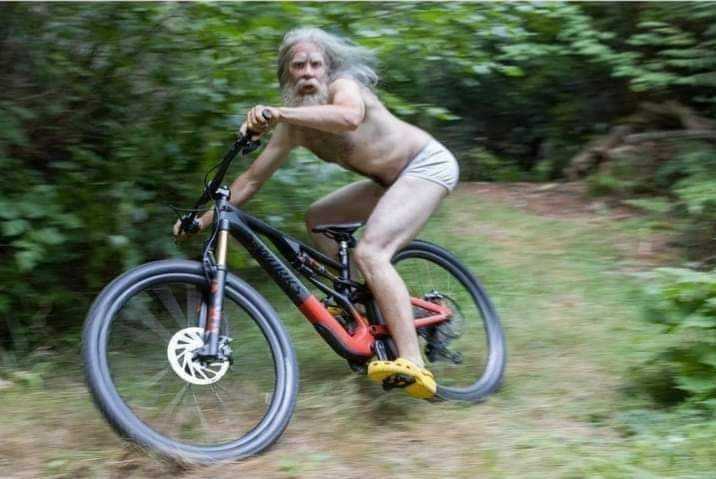 man riding a bike in the woods with no shirt on