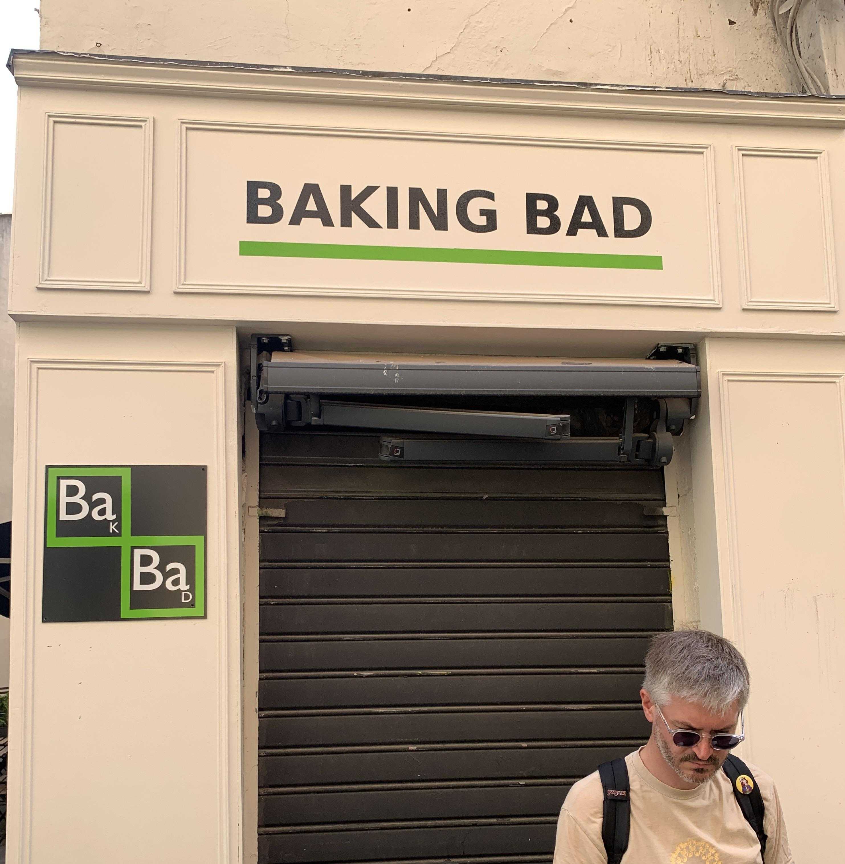 man walking past a building with a sign that says baking bad