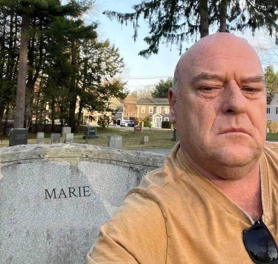 there is a man sitting on a stone bench in a cemetery