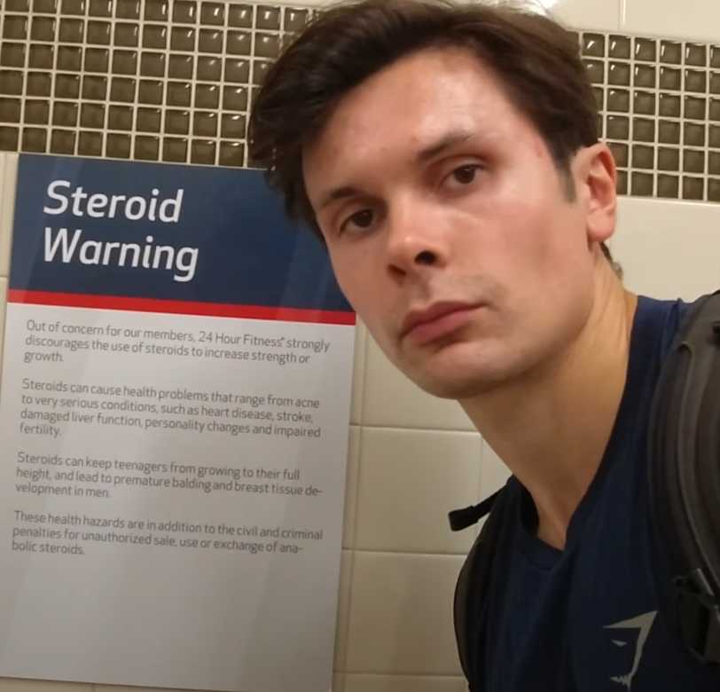 man in a blue shirt and backpack standing in front of a sign