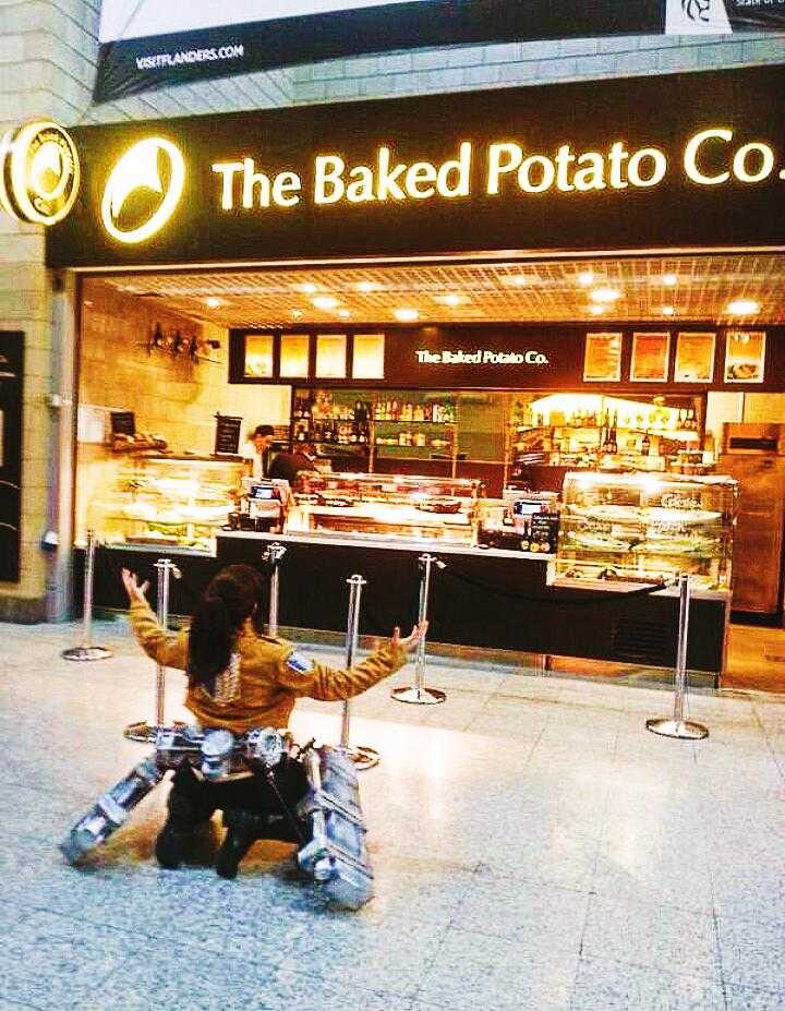 there is a little girl sitting on the ground in front of a bakery