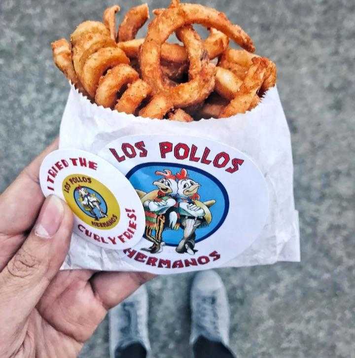 someone holding a bag of fried food with a sticker on it