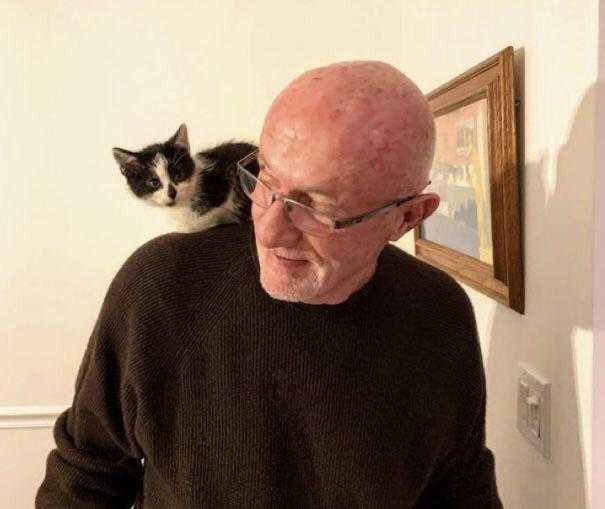 man with glasses and a cat on his shoulder