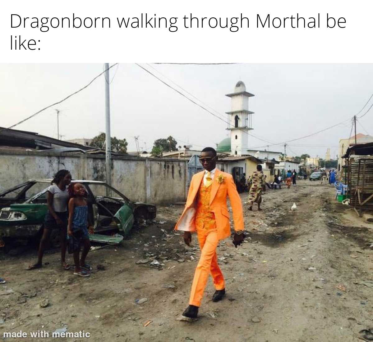 man in orange walking through a street with a mosque in the background