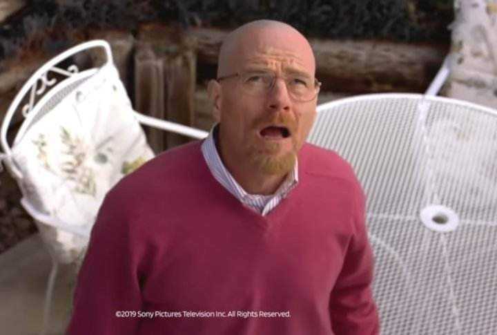 man in a red sweater standing in front of a white chair