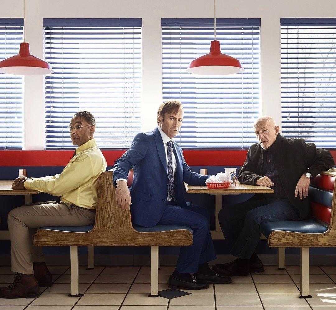 three men sitting at a table in a diner with red lamps