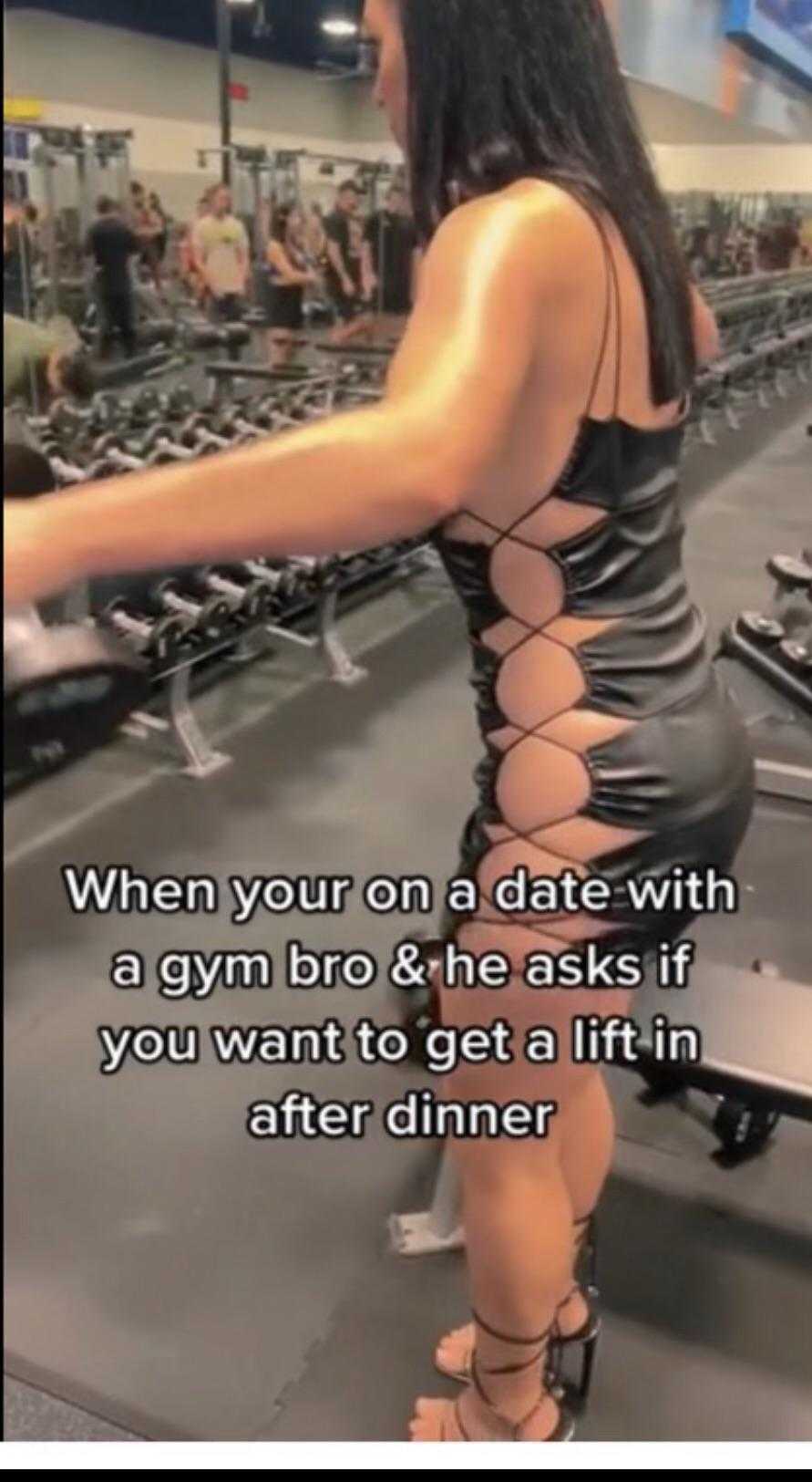 a woman in a black dress is standing in a gym