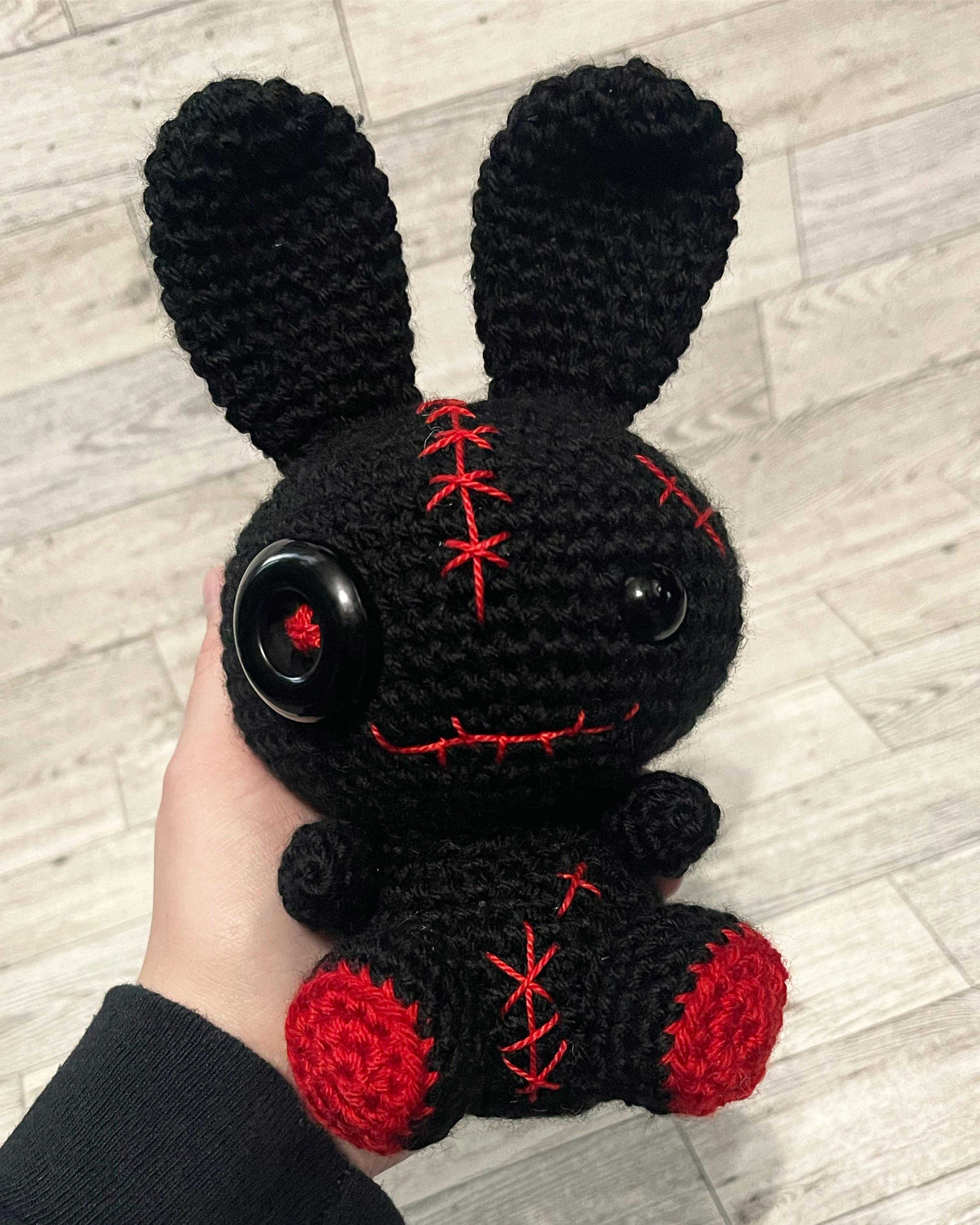 someone is holding a black and red stuffed animal with red stitches